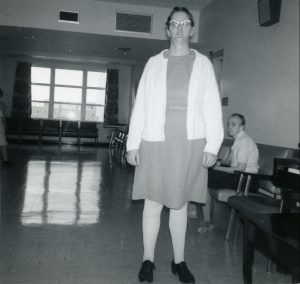 Doreen Befus standing in communal institutional room.