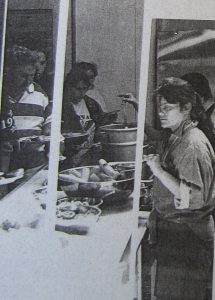 Two women serving food to a line-up of PARC members.