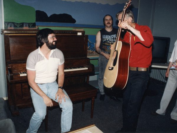 Man at piano and another man on guitar - laughing