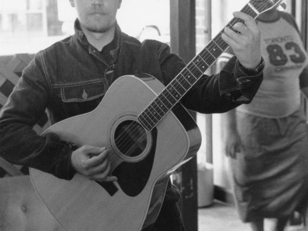 Man at doorway of PARC Drop-In with guitar