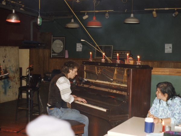 Man playing piano at PARC Drop-In with woman listening at table