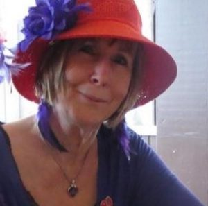 middle aged woman smiling, wearing beautiful red hat