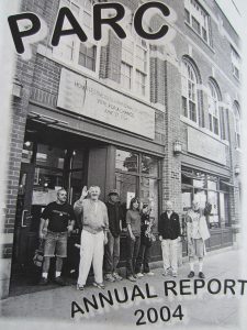 Photograph taken outside the front of PARC with group of seven PARC members waving to the person taking the picture