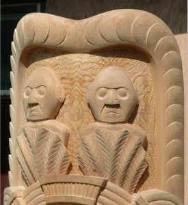 carved top of wooden totem pole with two figures